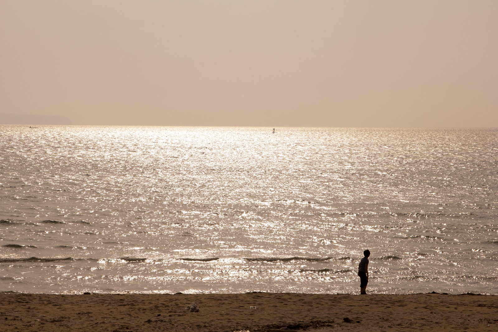 ひとり孤独に海辺に立っている少年と、海。